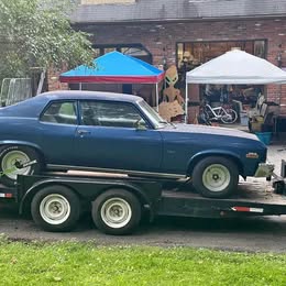 A Classic 1974 Chevrolet Nova two-door sedan & a dual-axle flatbed trailer.